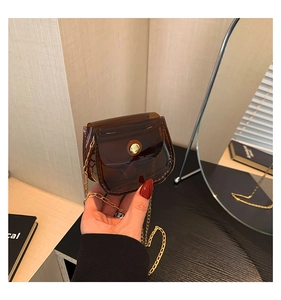 Détail d'un mini sac à main en PVC marron translucide avec chaîne dorée et bouton pression