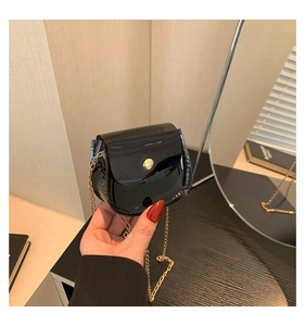 Détail du mini sac en cuir verni noir avec chaîne dorée et boucle métallique