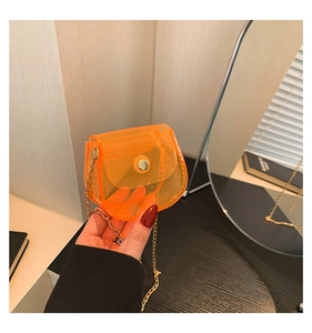 Détail d'un mini sac bandoulière orange transparent en PVC avec chaîne dorée et bouton