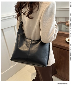 Close-up of black leather hobo bag with gold ring zipper detail on female model shoulder