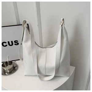 Macro shot of large white tote bag featuring gold ring accents and smooth leather texture