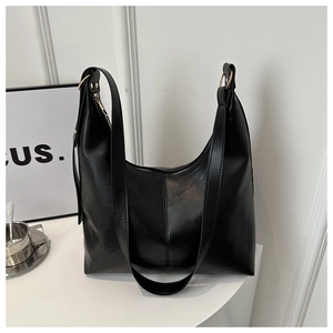 Detail of black leather hobo bag featuring gold metal rings and top zipper closure