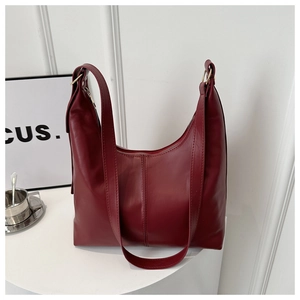 Detail of burgundy leather tote bag showing vertical stitching and gold metal hardware