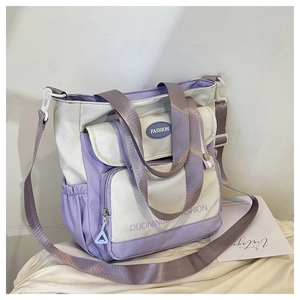 Detail einer großen Canvas-Beuteltasche mit lila-beigem Colorblocking und breitem Gurt