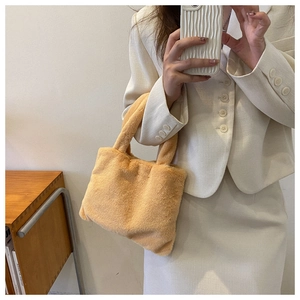 Close-up of fluffy apricot plush tote bag held by a model in a minimalist interior