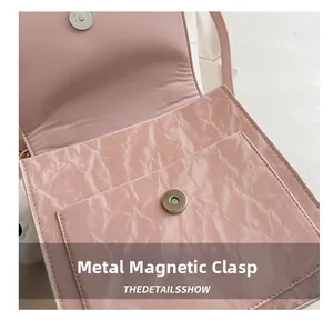Macro shot of hardware magnetic buckle and pink pleated texture on fashion bag