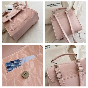 Detail view of pink crinkled leather backpack showing magnetic buckle and furry ball charm