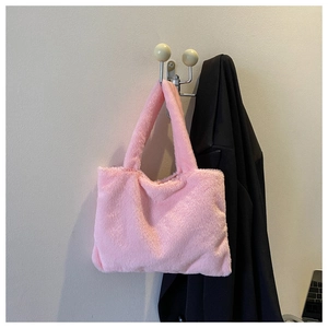 Detailed close-up of a pink faux fur tote bag hanging on a minimalist wall hook