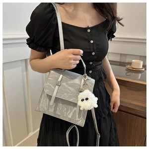 Detail of light gray pleated shoulder bag with cute white plush monster charm