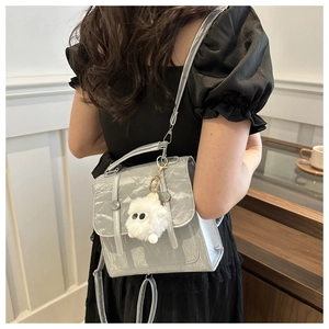 Detail of silver pleated texture backpack with a white plush monster charm pendant