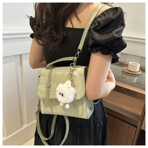 Detail of light green leather dual-use backpack with soft pleat texture and plush charm
