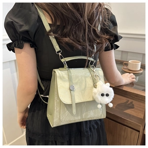 Green faux leather backpack with marble texture and white plush pendant shown on model