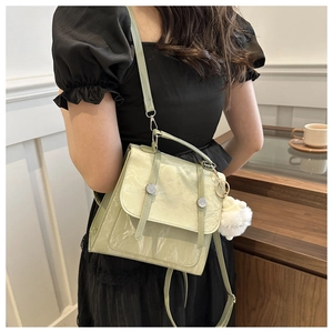 Detail of light green crossbody bag with textured leather, straps and plush pompom charm