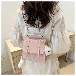 Detail of light pink embossed PU leather backpack with a cute white plush bear pendant