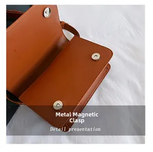 Dettaglio delle chiusure magnetiche argentate su una borsa a tracolla in ecopelle marrone