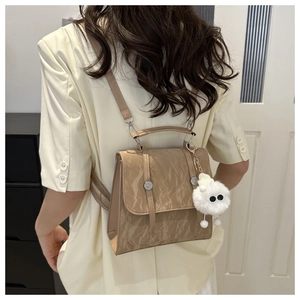 Detail of beige marble textured dual-use backpack with plush monster charm and metal rivets