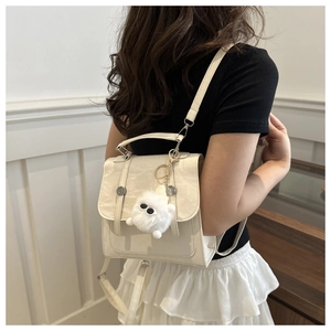 Detail view of cream white backpack with faux leather texture and plush monster charm