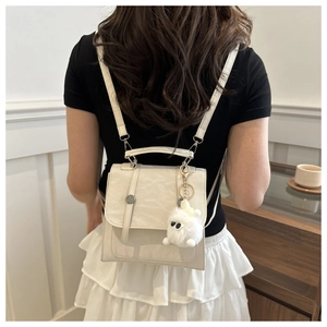 Detailed close-up of cream textured leather backpack with cute plush monster charm