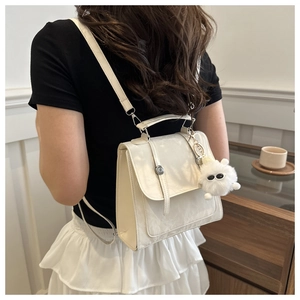 Close-up of cream PU leather backpack with a plush monster charm and fine texture