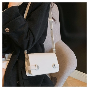 Dettaglio della borsa a tracolla in pelle bianca con fibbie argentate su cappotto