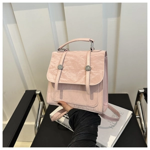 Detail view of pink pleated PU leather backpack with decorative metal buckles and top handle
