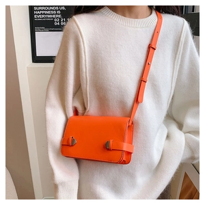 Dettaglio di una borsa a tracolla arancione brillante con fibbie argento e cinturino
