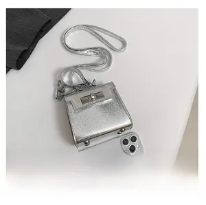 Detail view of mini silver laser metallic bag with turn-lock and smartphone comparison