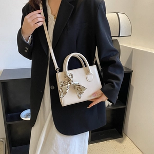 Minimalist creamy white square crossbody bag with silk scarf on a lifestyle model