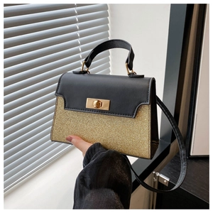 Detail of elegant two-tone handbag with black leather flap and gold sequin finish