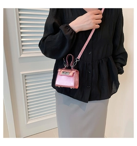 Detailed close-up of a mini metallic pink crossbody bag showing leather texture and handle