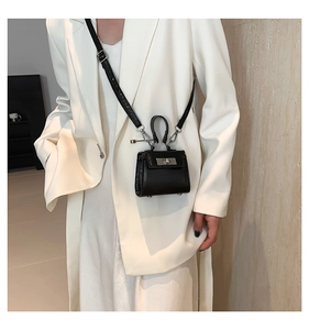 Macro detail of micro black leather bag featuring silver twist lock and minimalist design