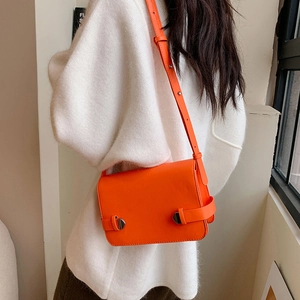 Borsa a tracolla quadrata arancione vivace con borchie argentate su top bianco