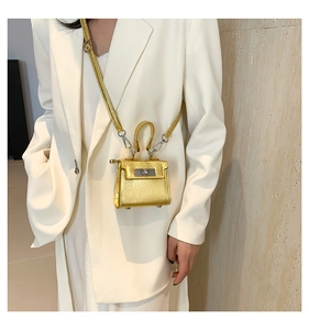 Detail of golden laser glossy mini bag showing metallic texture and silver turn-lock