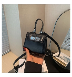 Detail of a black mini crossbody bag in shiny patent leather with silver hardware finish