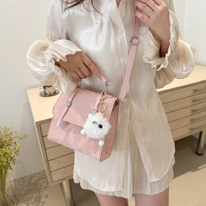 Pink leather crossbody bag with cute plush monster charm shown on a stylish model