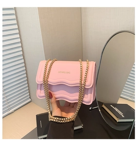 Detail of pink quilted crossbody bag with wave pattern and chunky gold chain strap