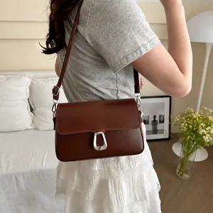 Detail view of the brown leather crossbody bag with silver U-shaped metal clasp