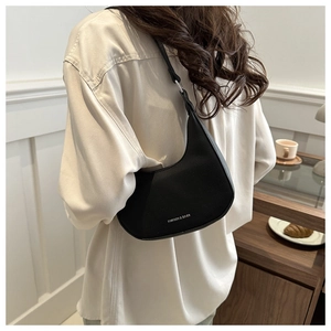 Detail of black pebbled leather hobo bag showing silver logo and shoulder strap texture