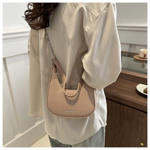 Detail of minimalist beige crescent underarm bag with litchi texture and chain strap
