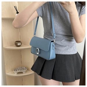 Detail of light blue rectangle leather crossbody bag with silver square buckle and strap