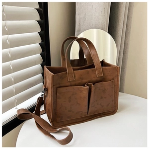 Close-up of brown vintage PU leather tote bag with dual front pockets and shoulder strap