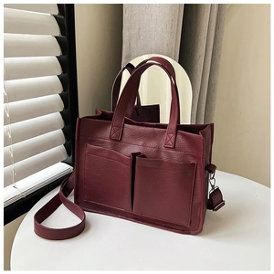 Detail of burgundy tote bag showing pebbled leather texture, dual pockets and strap