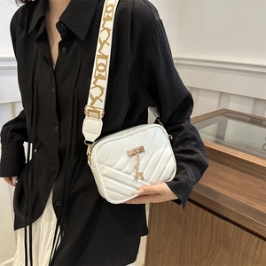 White quilted crossbody bag with V-shaped stitching and a golden deer charm pendant
