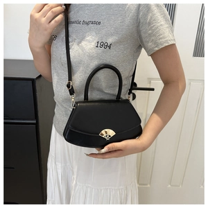 Détail du sac à main en cuir noir avec boucle métallique dorée en éventail et bandoulière