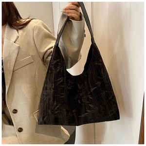 Detail of black shoulder bag with bamboo leaf texture on minimalist suit background