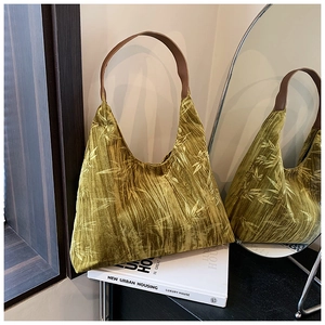 Detail of green velvet underarm bag with yellow bamboo leaf print and leather strap