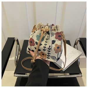 Detail of woven floral bucket bag with leather drawstring closure and textures