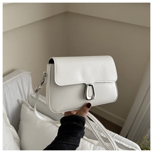 Close-up of a white leather crossbody bag featuring a unique silver metallic buckle