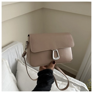 Detail of earthy brown leather crossbody bag with distinctive silver horseshoe buckle