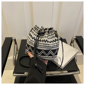 Close-up of geometric pattern drawstring bucket bag with leather strap and gold hardware